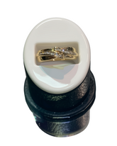 Two gold rings with small diamonds, displayed on a white oval stand inside a black ring box, isolated on a white background.