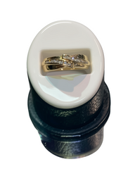 Two gold rings with small diamonds, displayed on a white oval stand inside a black ring box, isolated on a white background.